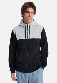 Felpa grigia e nera con zip, caratterizzata da un design bicolore, con una texture morbida, cappuccio regolabile con cordino e tasche frontali.