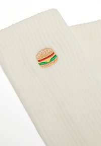Calcetines de color crema con canalé que presentan un diseño bordado de hamburguesa con pan de semillas de sésamo, lechuga y acentos en rojo y amarillo.