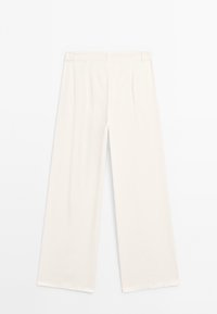 Pantalons larges en tissu blanc cassé avec une texture lisse, présentant des plis devant et un ourlet propre. Pas de poches visibles ni d'ornements.
