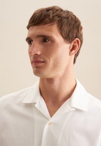 Witte shirt met korte mouwen, een puntige kraag en een knoopdetail. Gladde textuur, lichtgewicht stof en een relaxte pasvorm.