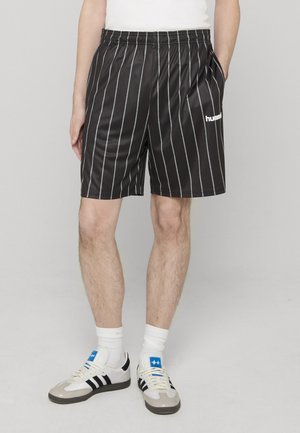 Pantaloncini neri con strisce verticali bianche, realizzati in tessuto liscio. Presentano una cintura elastica e un logo sulla gamba sinistra.