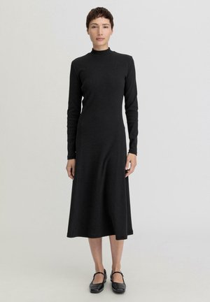 Black long-sleeve dress with a high neck, made of knit material. The design features a flared skirt and seamless side panels.