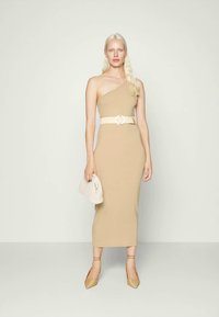 Vestido bege de um ombro com silhueta justa, cinto branco justinho, clutch texturizada e sapatos de salto dourados com tiras. Acabamento do tecido suave.