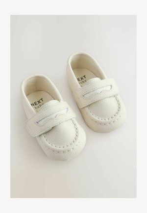 Valged beebijalatsid, mis on valmistatud tekstureeritud nahast, varustatud õmmeldud detailidega rihmaga ja pehme voodriga. Brändi nimi on sees nähtav.