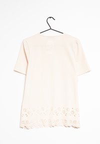 Top corto a maniche corte rosa chiaro con scollatura rotonda, caratterizzato da un orlo decorativo con tagli a scallop e motivi floreali. Realizzato in tessuto morbido.