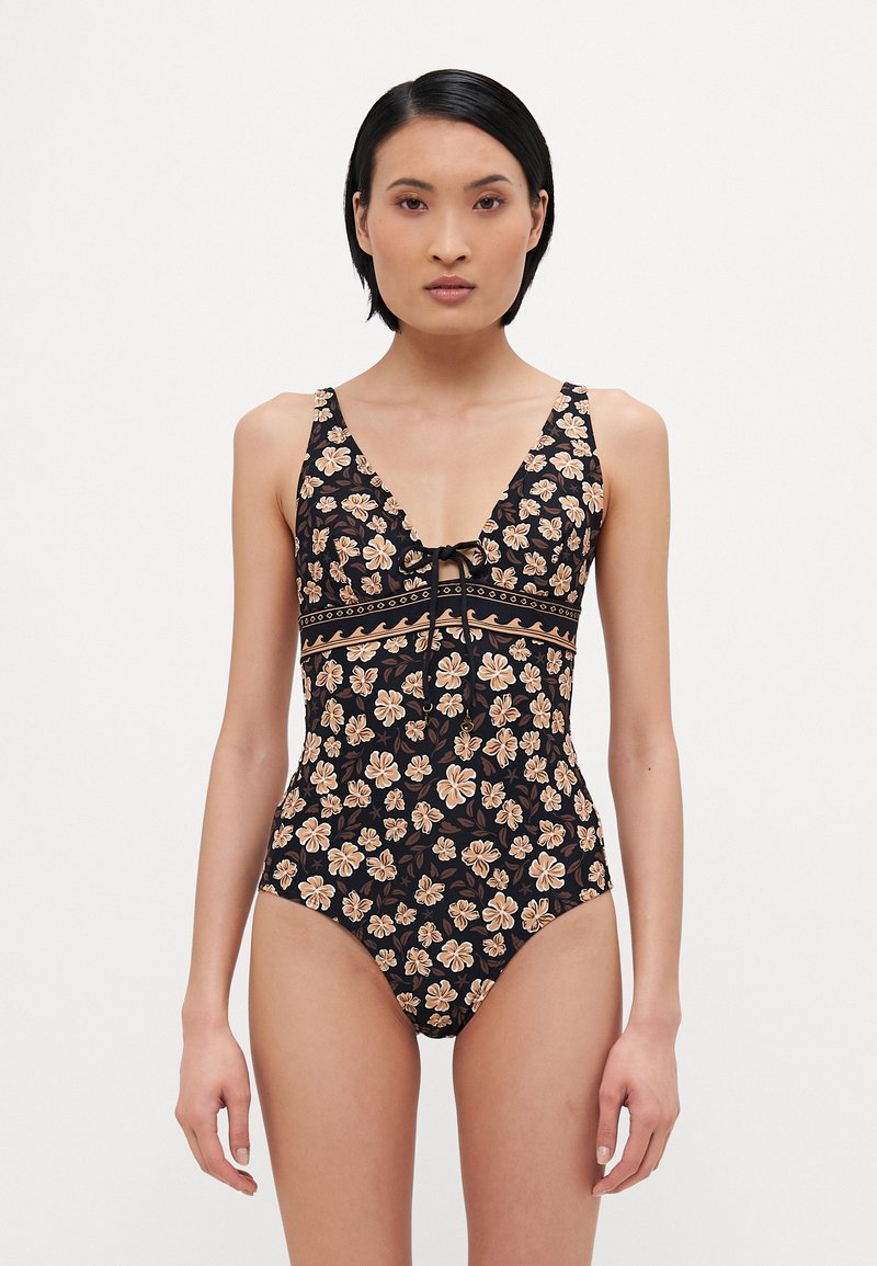 Maillot de bain une pièce noir avec un motif floral en beige et marron. Il présente un décolleté en V et un lien ajustable à l'avant.