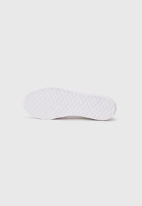White sneaker sole featuring a textured, grid pattern for traction. Smooth edges and no visible branding. Simple, minimalistic design.