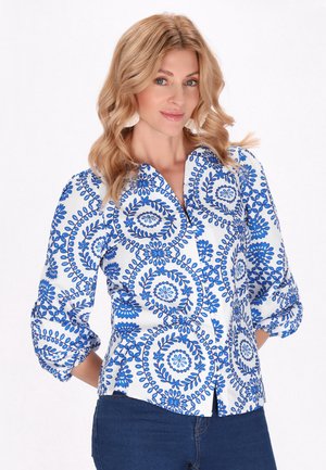 Weißes Bluse mit blauem Blumenmuster, Knopfverschluss-Design und drei Viertel-Ärmeln. Weicher Stoff mit einem leichten Glanz.
