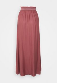 Lange, stoffige rozenroze rok met een geplooide hoge taille en vloeiende stof die tot de grond reikt, tegen een eenvoudige witte achtergrond.