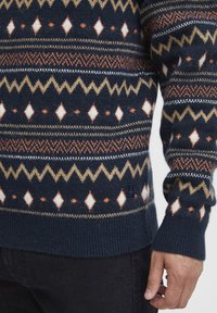 Pulover cu model marin, featuring diamante și designuri în zigzag în alb, portocaliu și bej. Manșete și tiv cu nervuri, realizat dintr-un material tricotat texturat.