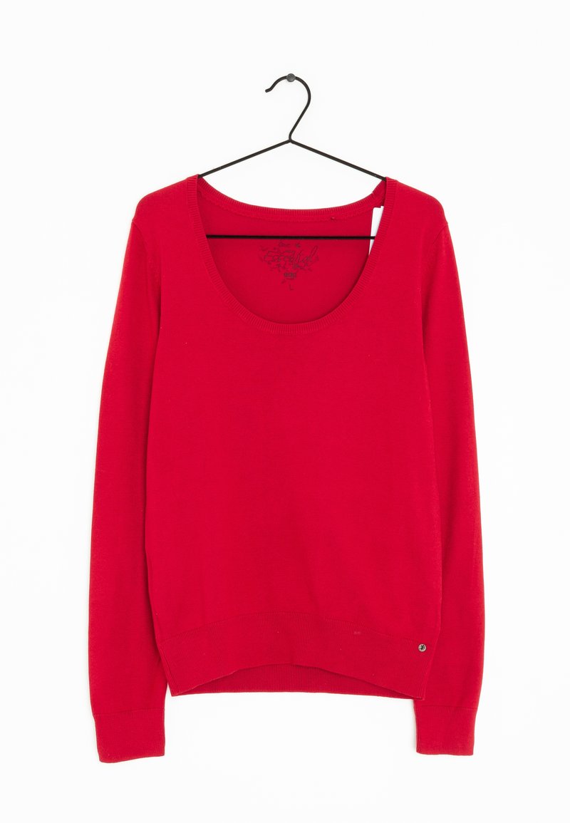 Pull rouge à manches longues avec encolure dégagée suspendu à un cintre en métal noir sur fond blanc.