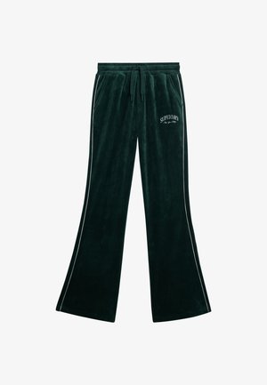 Zielone, aksamitne spodnie w stylu dzwonów, z elastycznym pasem i białymi paskami po bokach. Zawierają logo "SUPERDRY" w białym wykończeniu.