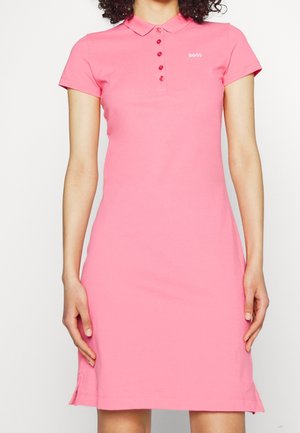 Woman wearing a pink short-sleeve polo dress with a collar and five buttons, featuring the "BOSS" logo on the chest.