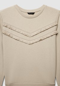 Sweatshirt beige présentant des accents de franges superposées en motif chevron sur la poitrine, avec un col rond et des poignets côtelés.
