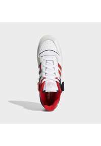 Baskets blanches Adidas avec des rayures rouges et bleu marine, des lacets blancs et une doublure intérieure rouge, vues du dessus sur un fond gris clair.