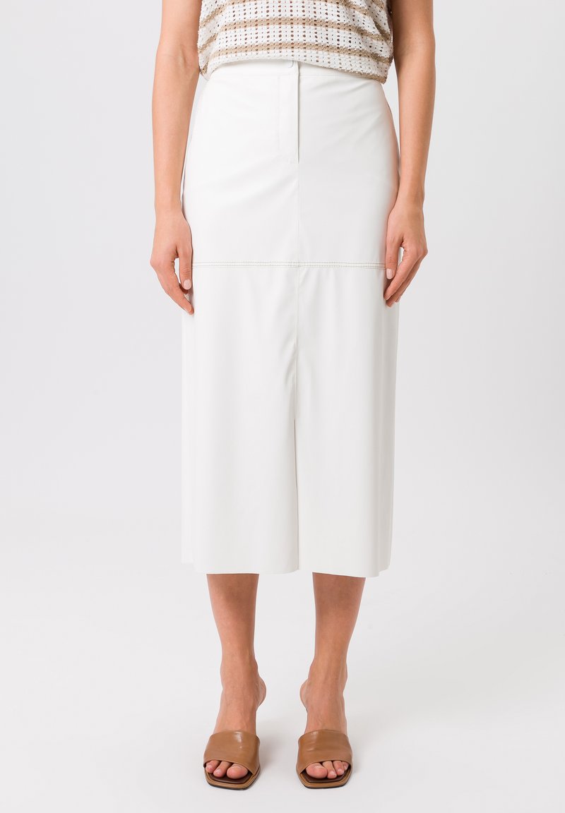 Witte, hoge taille rok van nepleer, met een knielengte en subtiele naaddetails. Gecombineerd met bruine sandaal met open tenen.