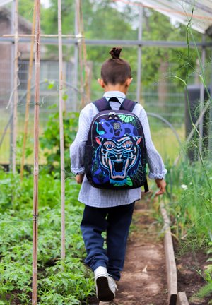 Zwarte rugzak met een kleurrijk tijgergezicht ontwerp, omringd door groene bladeren en blauwe accenten; gedragen door een kind in een gestreepte shirt.