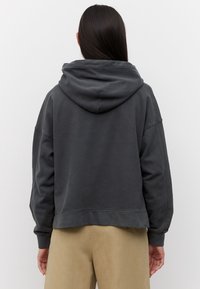 Grijze cropped hoodie van zachte stof, met een grote capuchon en een losse pasvorm met aflopende schouders. Zichtbare naden en geribbelde manchetten.