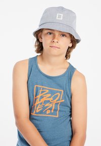 Grijze bucket hat van een gestructureerde stof met een klein logo-patch, gecombineerd met een blauwe mouwloze shirt met oranje grafische tekst.