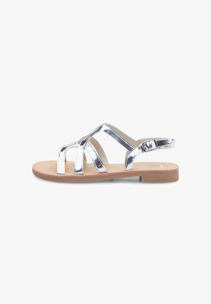 Zilveren metallic sandaal met banden en een platte, beige zool, voorzien van een verstelbare enkelgesp en een open teen ontwerp. Gladde materialen en een minimalistische stijl.