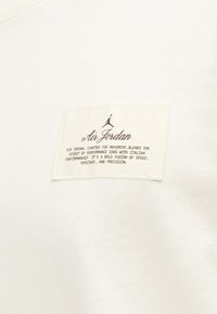 Ετικέτα Air Jordan σε λευκό ύφασμα με το λογότυπο Jumpman και κείμενο για τη συνδυασμό επιδόσεων αυτοκινήτων και ιταλικής δεξιοτεχνίας.