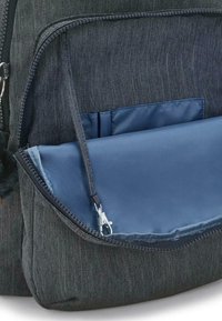 Grå denimryggsäck med en blå nyloninsida. Har en zippered ficka och synliga sömdetaljer. Strukturerad, kompakt design.
