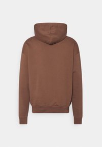 Felpa con cappuccio marrone a vestibilità rilassata. Texture morbida, polsini e orlo a costine e un design semplice senza loghi o motivi visibili.