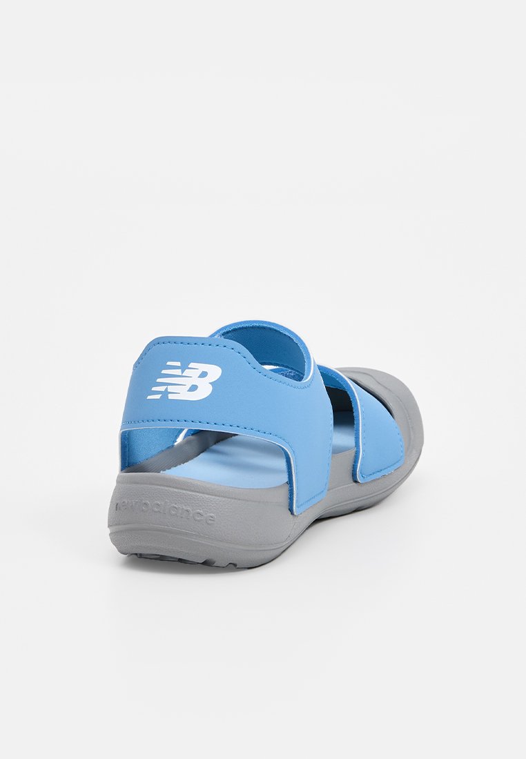 Sandalia de color azul claro con suela gris, diseño moldeado, correas ajustables y un logo en la parte trasera. Fabricada con material sintético para mayor comodidad.