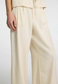 Beige brede bukser med plisseringer, lavet af glat stof. Designet har en afslappet pasform og en justerbar snor i taljen.