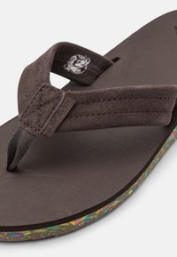 Brown flip-flop with a textured footbed and two fabric straps. The outsole features colorful flecks, providing a contrasting detail.