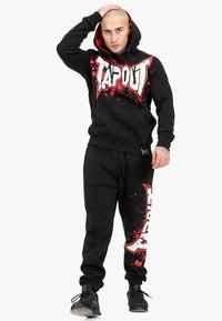Black hoodie with red accents and white "TAPOUT" graphics, paired with matching black sweatpants featuring similar designs and splatter details.