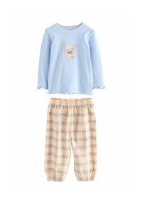 Cămașă albastru deschis cu mânecă lungă și broderie cu urs; pantaloni de pijama bej cu carouri, cu talie elastică și manșete strânse.