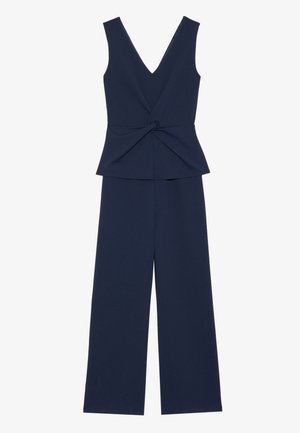 Combinaison navy avec décolleté en V, sans manches, dotée d'un détail avant torsadé et de pantalons évasés. Fabriquée à partir d'un tissu doux.