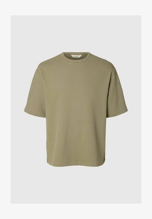 Olivovozelené tričko s krátkym rukávom, okrúhlym výstrihom a vzorom vaflového pletenia, voľného strihu a malou bielou značkou vo vnútri goliera.