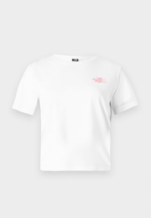 Osoba o kręconych włosach w białym skróconym T-shircie z pomarańczowymi kwiatami i napisem "The North Face" na plecach.