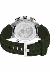Montre en acier inoxydable Timex avec un fond gravé représentant un globe, boutons, bracelet en silicone vert foncé et fermoir en argent.