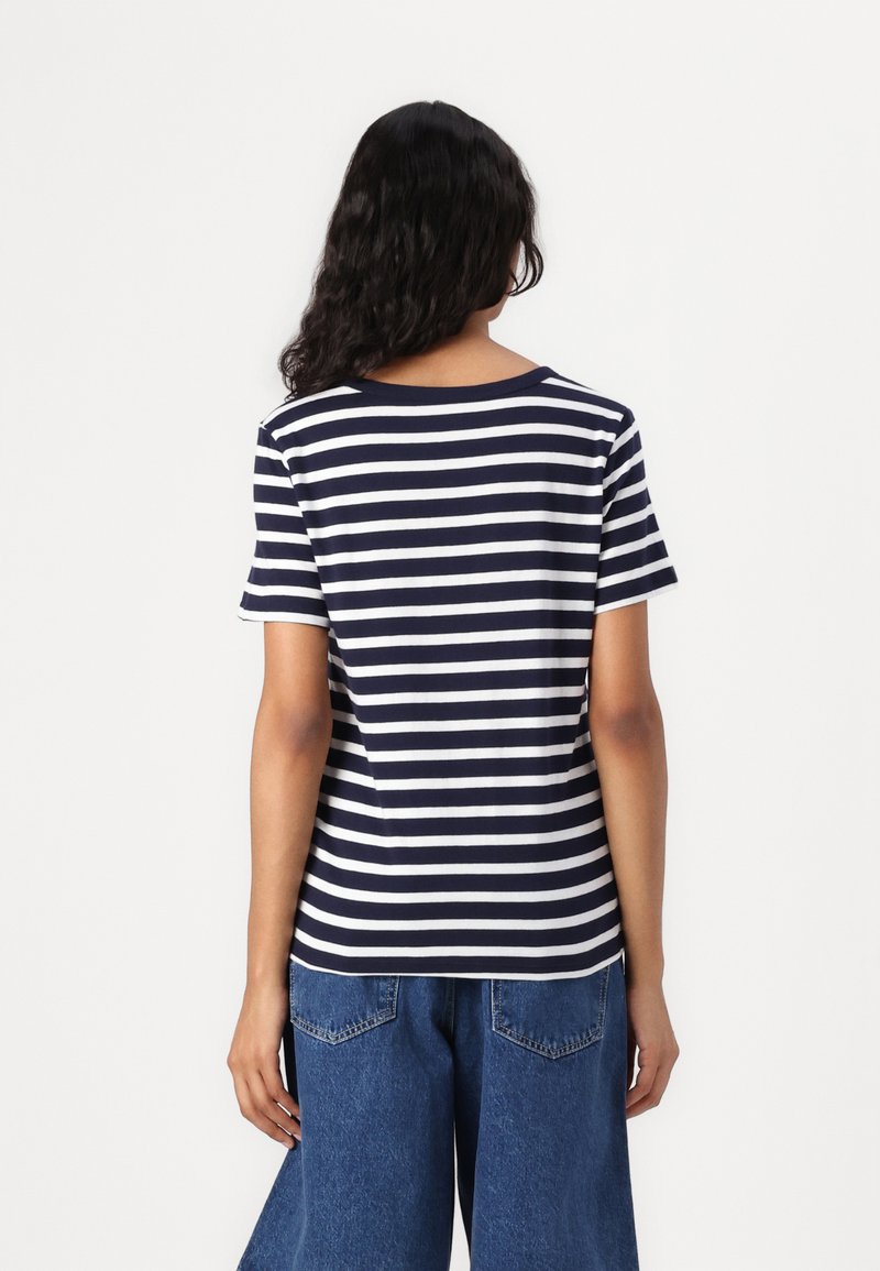 Morska koszulka w białe paski z krótkimi rękawami, okrągłym dekoltem i lekkiego materiału, w połączeniu z niebieskimi dżinsami o wysokim stanie.