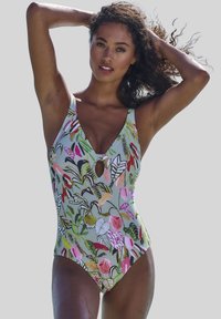 Costume intero di colore verde chiaro con motivi floreali e fogliari multicolori. Presenta una scollatura a V profonda e un piccolo taglio a forma di chiave sul petto.
