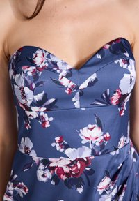 Vestido floral sin tirantes de tela azul marino. Cuenta con un escote corazón, pliegues y un vibrante patrón floral en rosa y blanco.