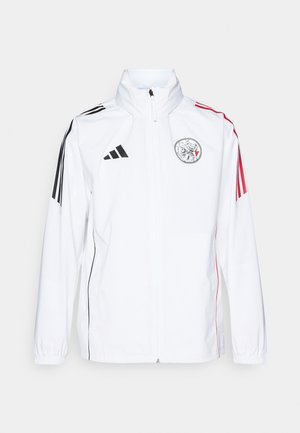 White adidas jacket with black accents, red stripes on sleeves, high collar, and an embroidered logo on the left chest; smooth texture.