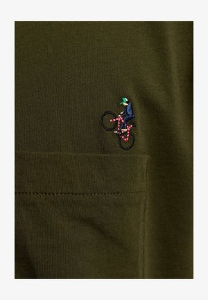 Olijfgroene stof met een gladde textuur heeft een klein geborduurd ontwerp van een fietser in donkerblauw en roze, met een groene pet.