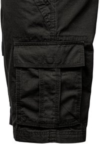 Black cargo pants made of durable fabric, featuring multiple textured pockets and vertical seam lines for added detail and functionality.