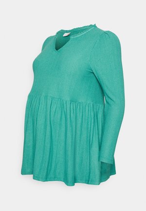 Top de maternidade malha verde com colarinho franzido, mangas longas e linha de cintura larga. Tecido texturizado com padrões subtis.