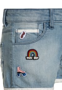 Denim shorts van een lichtblauwe stof, met een rafelige zoom en drie geborduurde patches: een regenboog, een rollerskate en een 'Boom' label.
