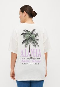 Biele overrozmerné tričko s grafikou palmy, nápisom "ALOHA" v purpurovej farbe a textom "Kauai, Hawaii, PACIFIC OCEAN". Jednoduchý dizajn s krátkymi rukávmi.
