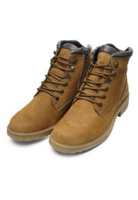 Een paar lichtbruine leren enkellaarsjes met bruine gewatteerde kraagjes, ritssluitingen aan de zijkant en ronde beige zolen op een witte achtergrond.