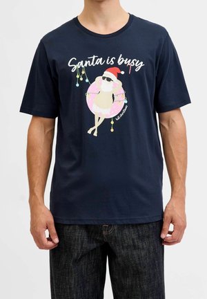 Chemise bleu marine avec un Père Noël détendu portant des lunettes de soleil, un short de bain et une bouée, avec le texte "Santa is busy" et des guirlandes lumineuses de Noël suspendues.