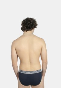 Slip in cotone blu navy con fascia elastica grigia con marchio, design aderente e trama liscia, visti da dietro.