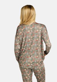 Vzorec rjavih pižam z igrivimi motivi živali in narave, z dolgimi rokavi in sproščenim krojem ter mehko, gladko teksturo.