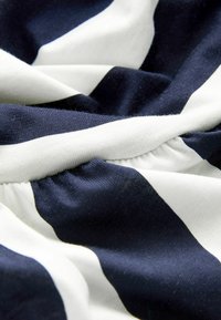 Marinblå och vit randig tyg med en mjuk, slät textur; har insamlade detaljer som visar en blandning av djärva linjer och mjuka draperingar.